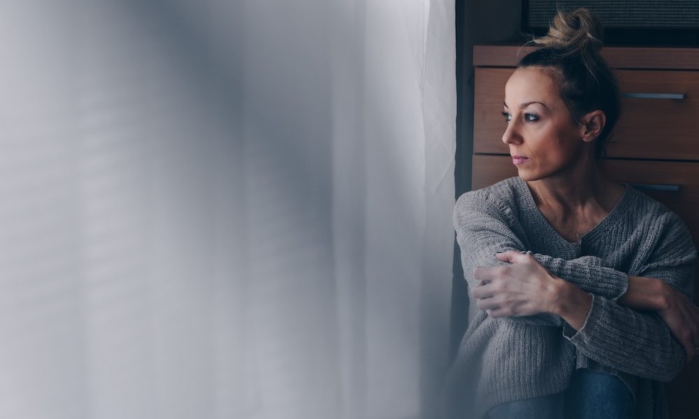Beautiful sad woman sitting on the floor looking at the window. Tech-assisted peer therapy effective for perinatal depression in lower income countries