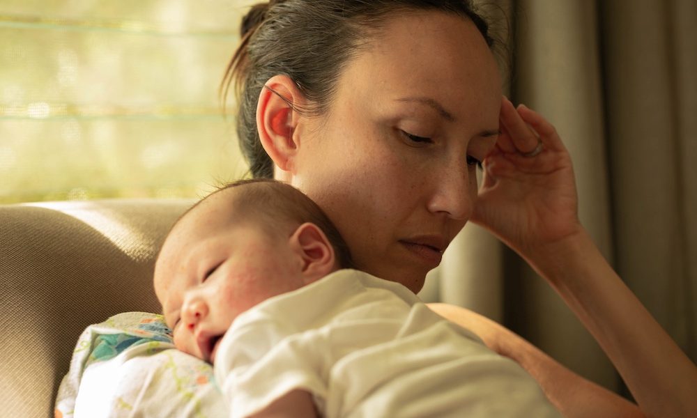 A unhappy mother suffering from postpartum depression, carrying her baby. Research finds inequities in treatment of postpartum depressive symptoms