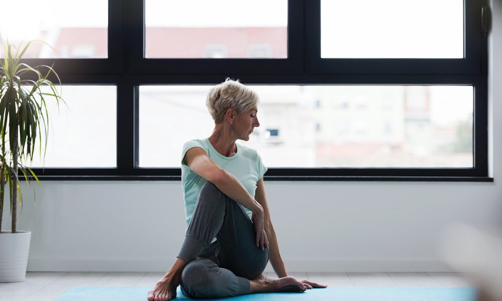 Active senior woman practicing yoga indoors. Exercise for Older Adults Digital clinic introduces movement-based menopause support