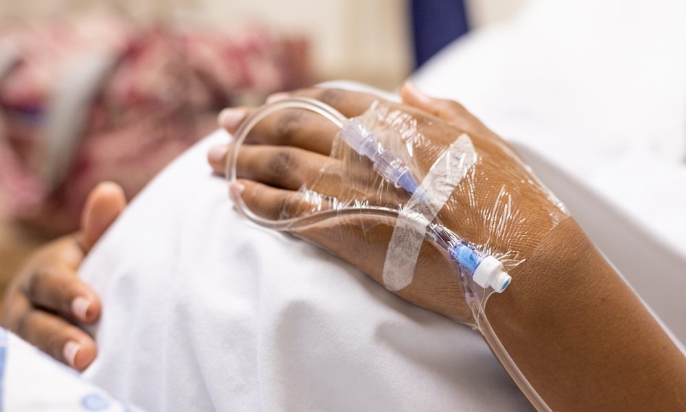 An image of a pregnant lady lying in a hospital bed holding her tummy, with a close up on the drip in her hand Emergency care during pregnancy could signal greater risk for severe maternal morbidity
