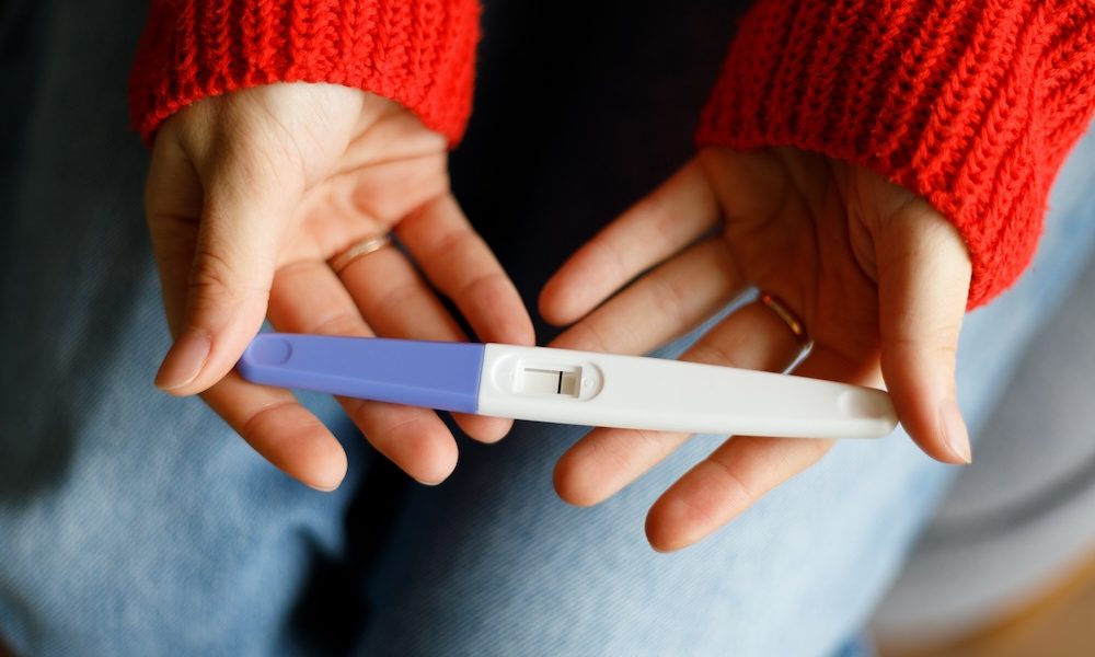 Negative pregnancy test with one strip in female hands, close-up. ‘Long waiting lists and patchy care provision’- NHS-funded IVF cycles fall to 14-year low