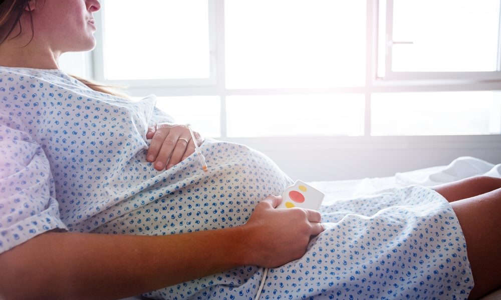 Pregnant woman lay in hospital bed with catheter in hand close view of belly Caesarean births overtake natural vaginal deliveries in England for first time