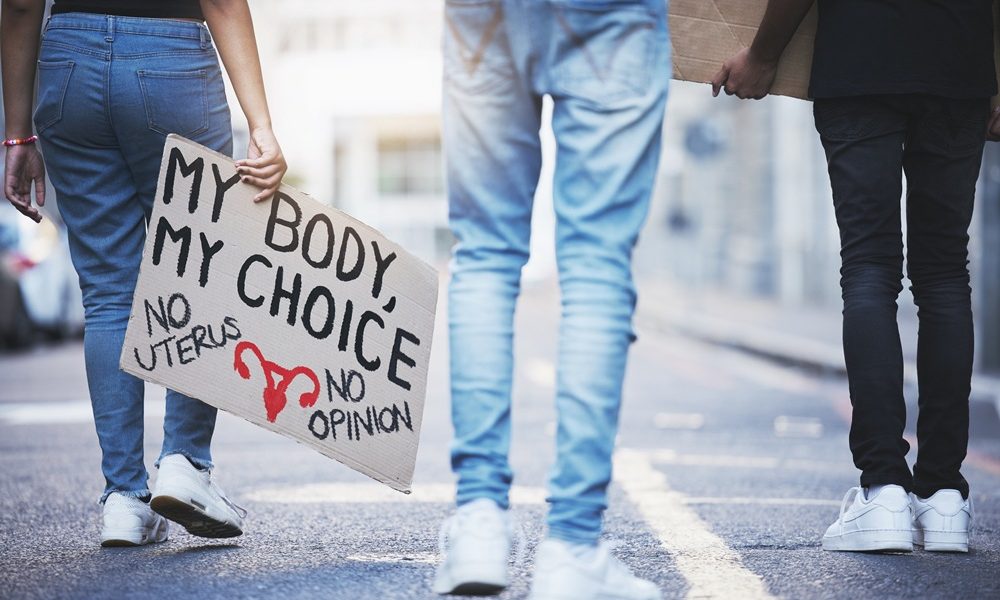 body-sign-abortion-protest-people-walking-legal-justice-freedom-choice-support-law-city-woman-man-supreme-court-activism-against-constitution-rights-with-poster State abortion bans linked to spike in maternal deaths, study finds