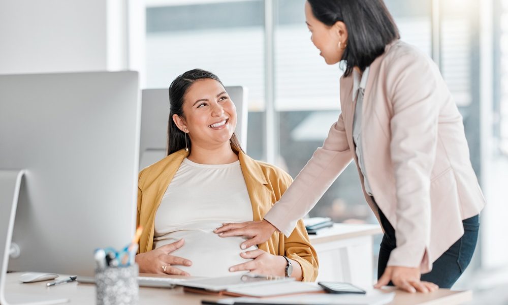 pregnancy-friends-touch-office-workplace-by-computer-with-colleague-smile-talking-with-future-mom-pregnant-woman-desk-happy-chat-support-career-women-abdomen-desktop Time off for fertility treatment: A necessity, not a work perk