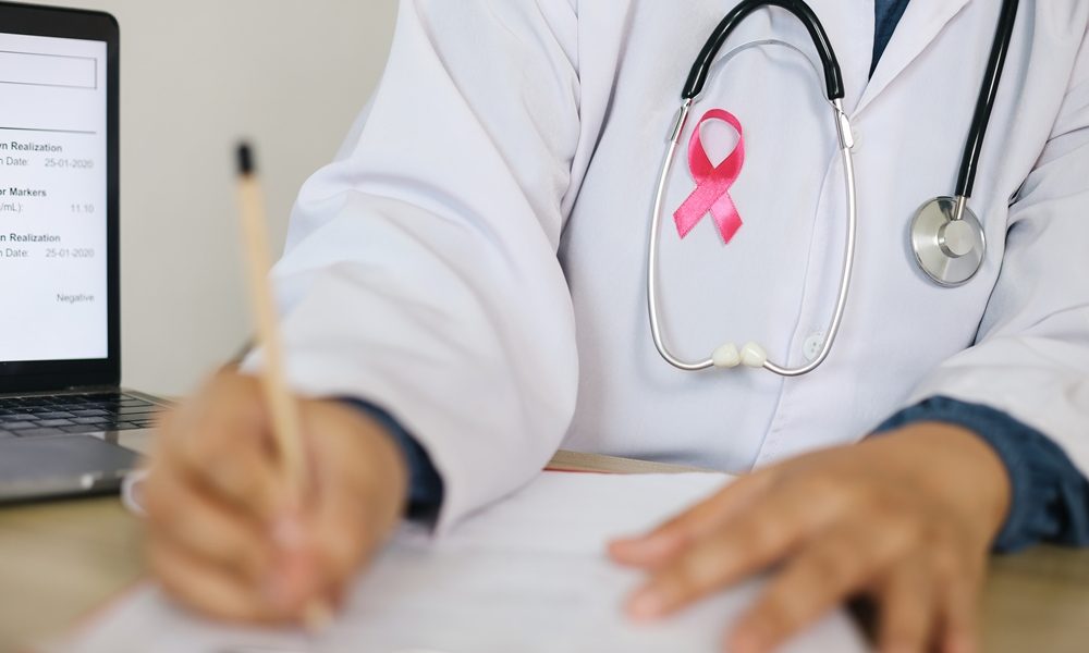 doctor-with-white-coat-writting-medical-document-wearing-pink-ribbon-stethoscope Thousands of women could avoid painful cancer exam with new AI blood test