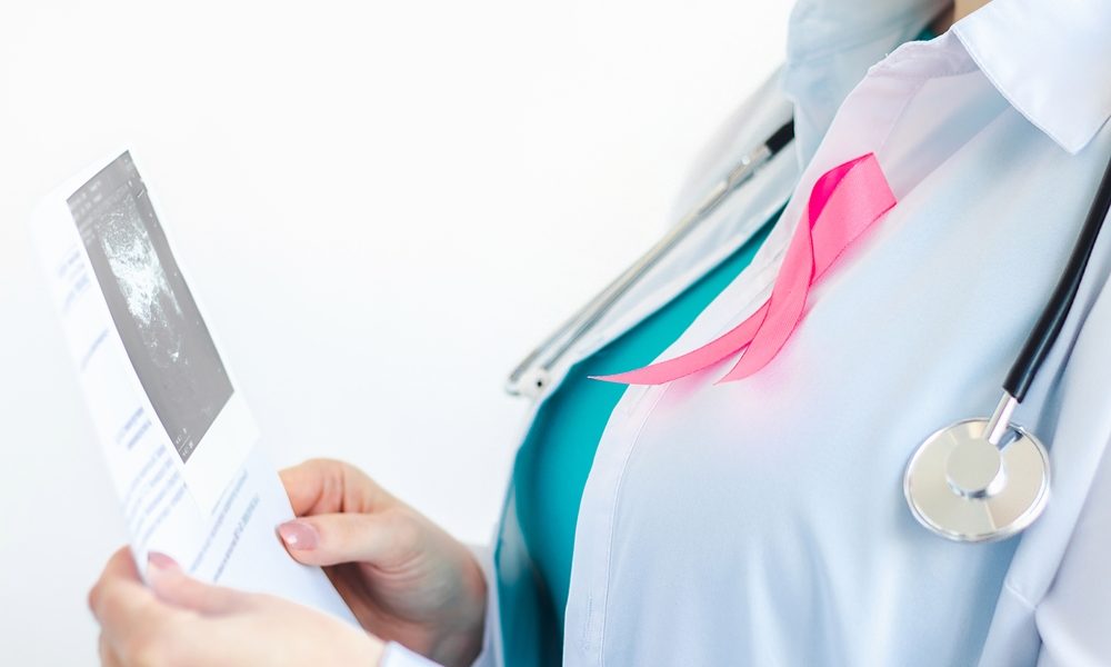 woman-doctor-with-pink-ribbon-white-medical-uniform-holds-results-ultrasound-scan-her-hands-breast-cancer-awareness-month-symbol-health-care-concept-copy-space-selective-focus The most measured cancer in women’s health still decides half its cases without the measurement